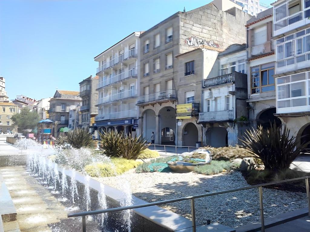 una fontana in mezzo a una strada con edifici di DADO HOST a Vigo