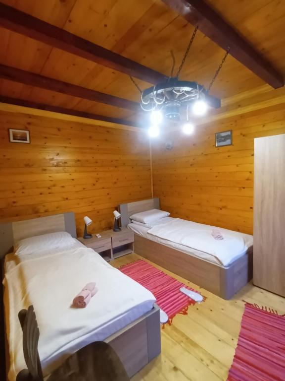 two beds in a room with wooden walls at Dvokrevetne Sobe - Snežana in Ležimir