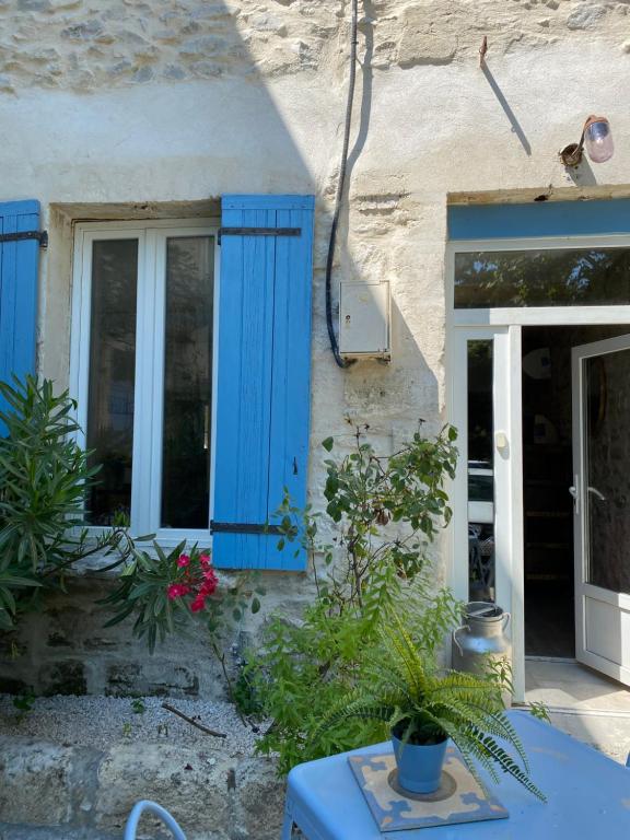 a house with blue shutters and a table with plants at Appartement Les Cyprès de l’Île in Avignon