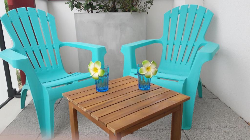 deux chaises bleues et une table en bois avec des fleurs dessus dans l'établissement Superbe T3 récent 67 m2, gde terrasse, 3km plage, vue Canigou, parking et box privatif, à Saint-Cyprien