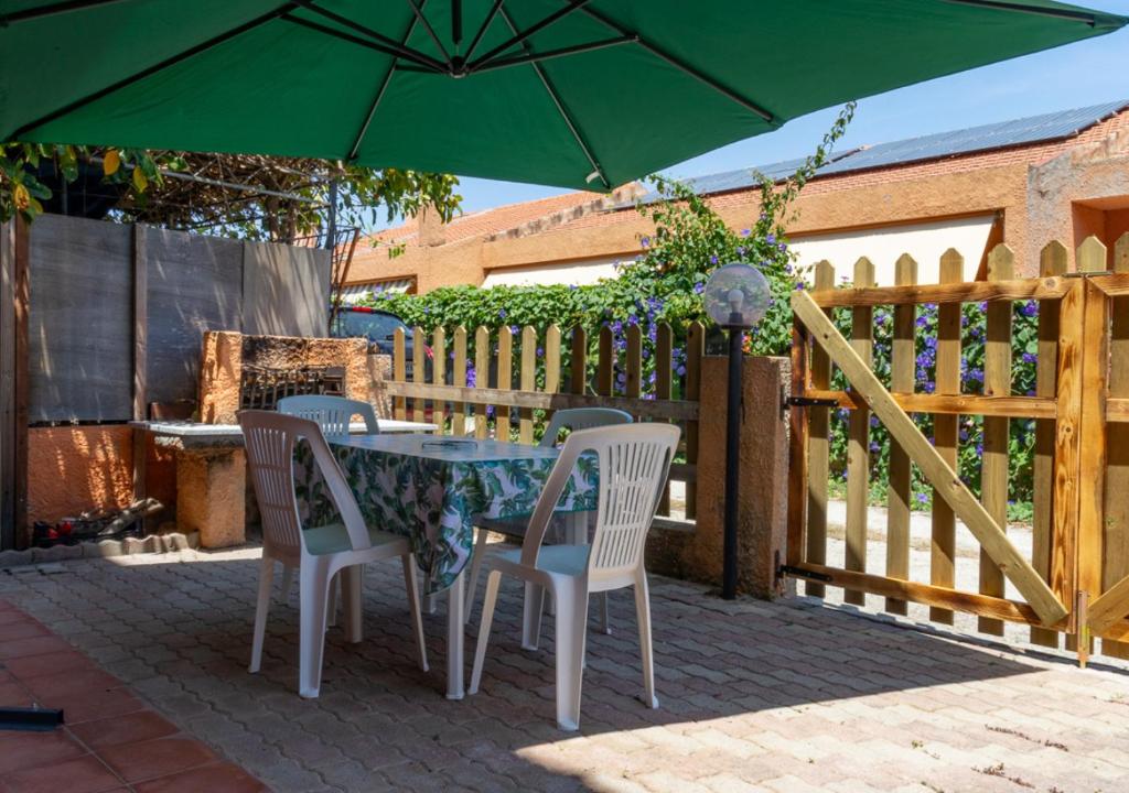 a table and chairs with a green umbrella on a patio at Taverna Porto Conte in Porto Conte