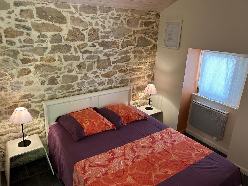 Monclar-de-QuercyにあるLa Forestière Pigeonnierの石壁のベッドルーム1室(ベッド1台、ランプ2つ付)