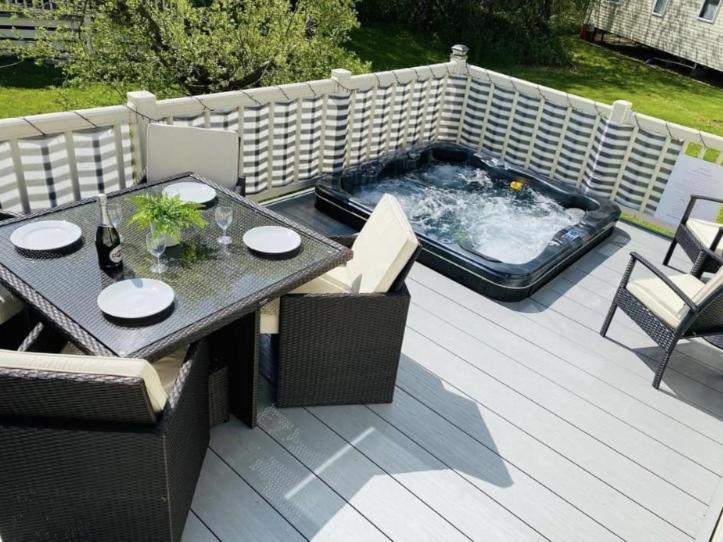 a table and chairs on a deck with a hot tub at Prime Location & Luxurious Hot Tub in Tattershall