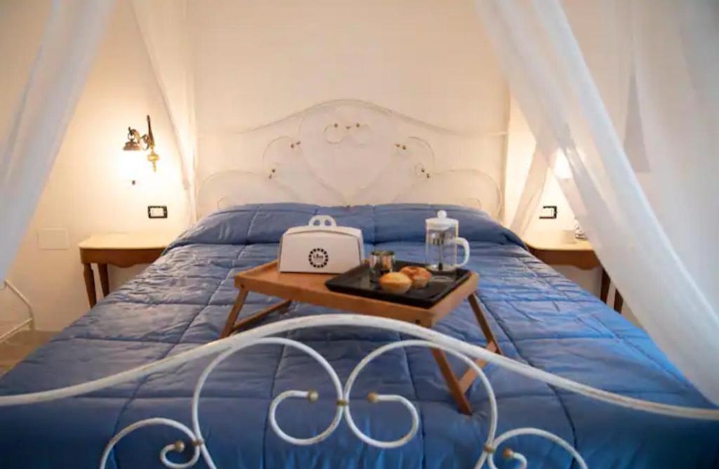 una camera con un letto blu e un vassoio di B&B Visìta_experience a Torre Santa Susanna
