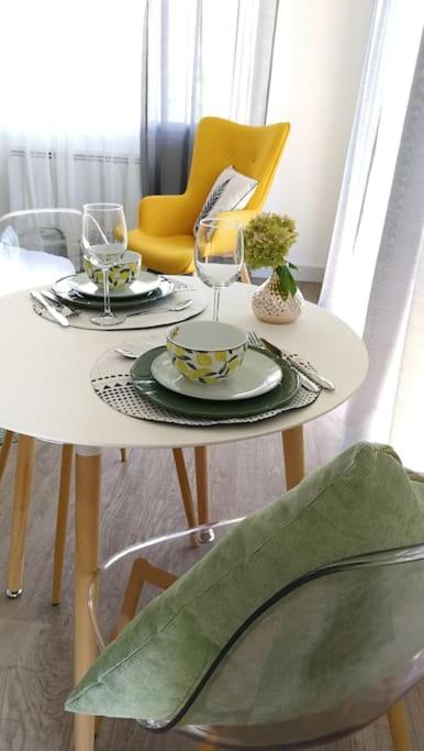 une table blanche avec deux assiettes et des verres dessus dans l'établissement 555 Appartement calme et climatisé au cœur du village, à Brazey-en-Plaine