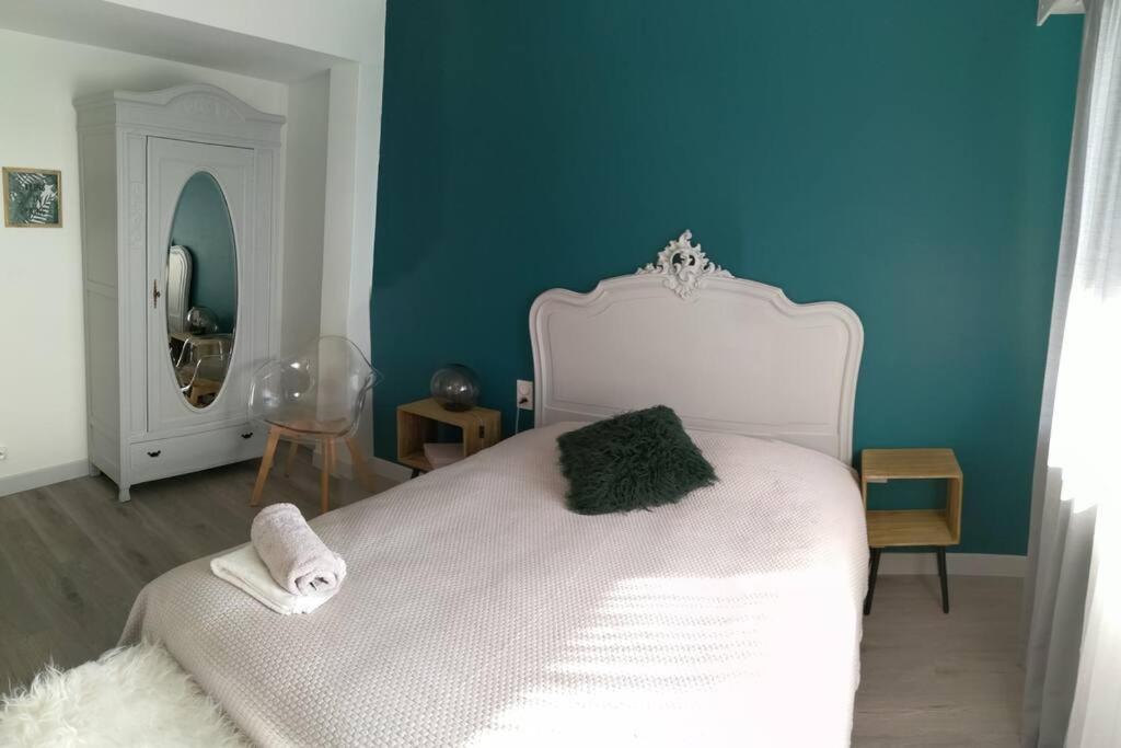 a bedroom with a white bed with a blue wall at Appartement calme et climatisé au cœur du village in Brazey-en-Plaine