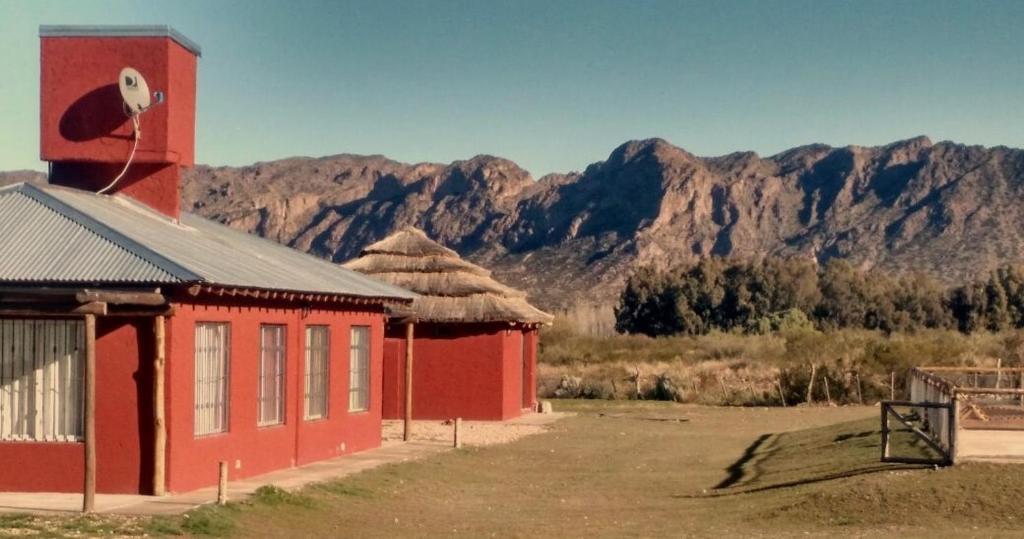un edificio rojo con una montaña en el fondo en Cabañas Vistas Andinas en Valle Grande