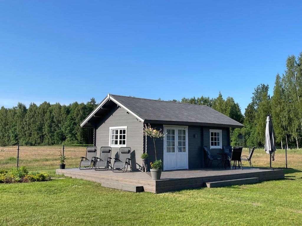 a small cabin with a deck in a field at Piejūras Kaķīšu namiņš in Ķesterciems