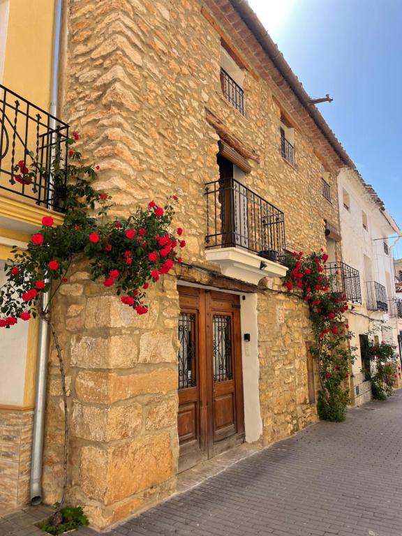 un bâtiment avec des fleurs rouges sur son côté dans l'établissement Casa Rural Aras Apartamentos Turísticos, à Aras de Olmos