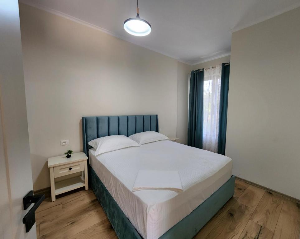 Schlafzimmer mit einem Bett mit blauem Kopfteil und einem Fenster in der Unterkunft Cozy PineTrees Beach House in Golem