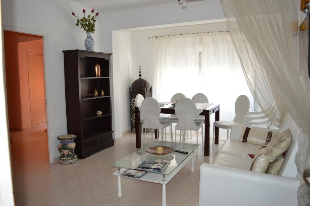 Apartamentos de las Heras في مدينة إيبيزا: غرفة معيشة مع طاولة وكراسي بيضاء