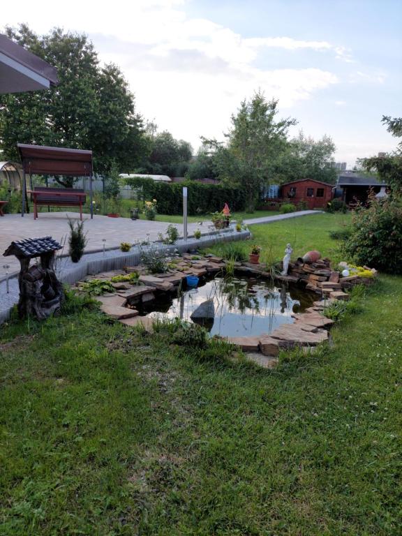 - un jardin avec un étang et un banc dans une cour dans l'établissement Apartmán Tatiana, à Smižany