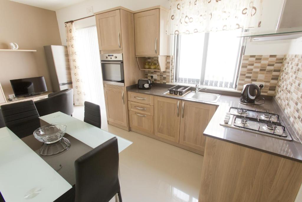 cocina con armarios de madera y encimera en Waterside Apartments, en Marsalforn