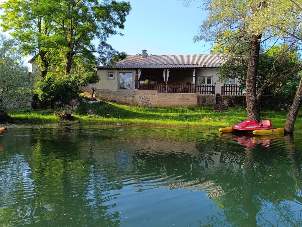 a house on the river with two canoes in the water at River house Golac in Gospić
