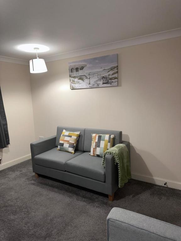 a living room with a gray couch with pillows at 2 Bed Apartment Sleeps 5, Free Parking, Free Wifi, Spacious, Quiet, Close to Station, Restaurants & Shops, Contractors and Holidays in London