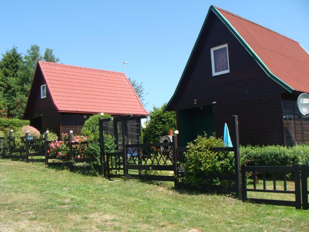 Czarny dom z czerwonym dachem i płotem w obiekcie Domki u Uli w mieście Jarosławiec