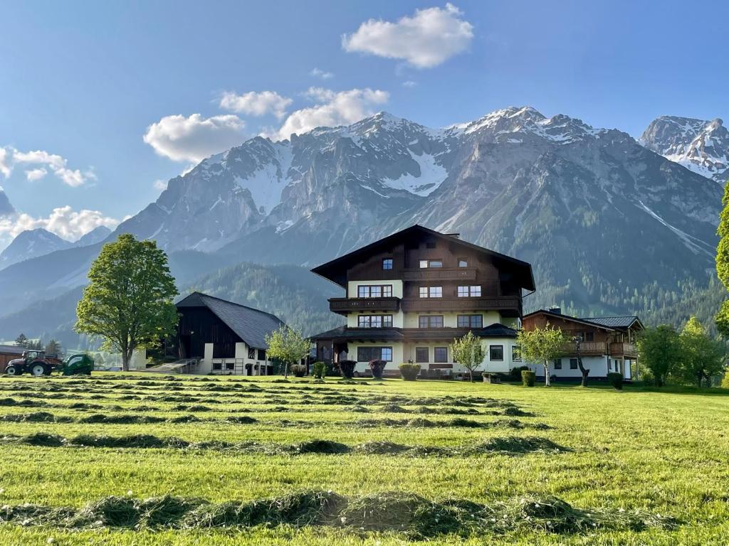 una casa en un campo con montañas en el fondo en Pension Möslehnerhof, en Ramsau am Dachstein