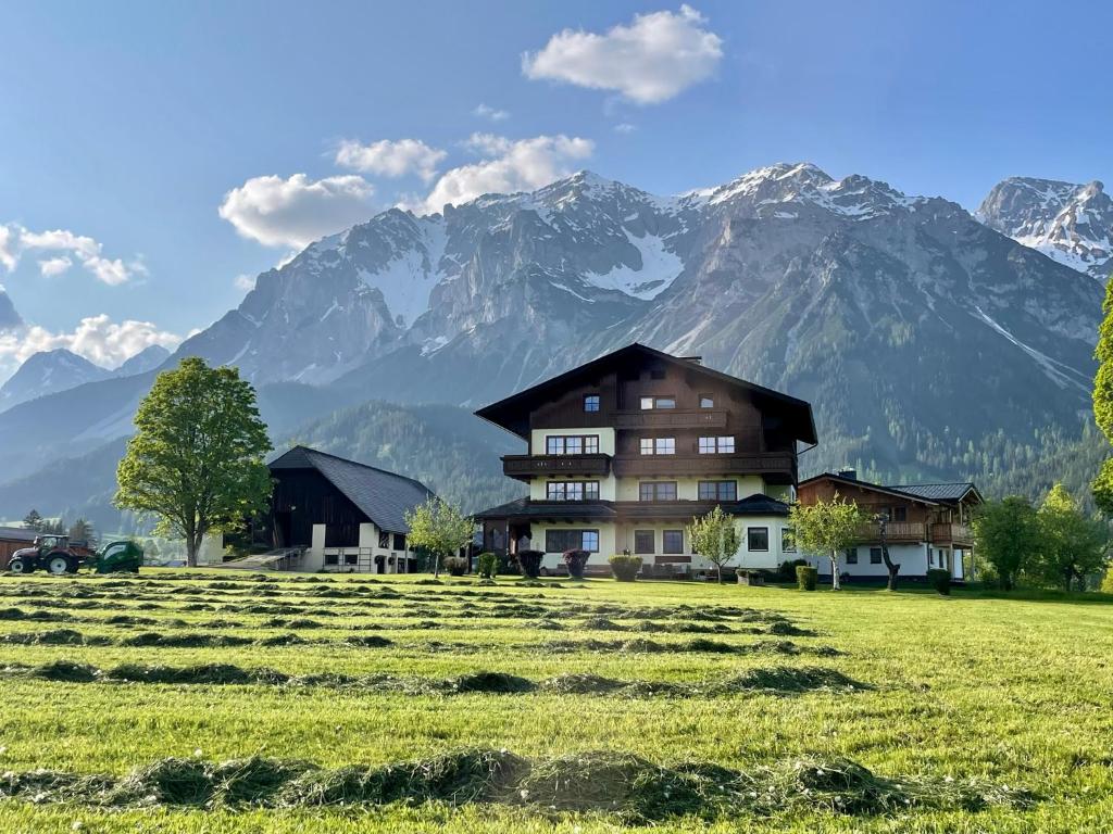 a house in a field with mountains in the background at Pension Möslehnerhof in Ramsau am Dachstein
