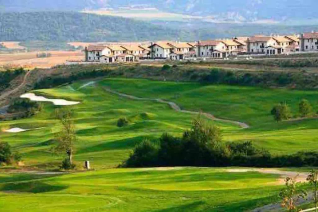 un campo de golf verde con casas en el fondo en Un encanto de dúplex en Jaca