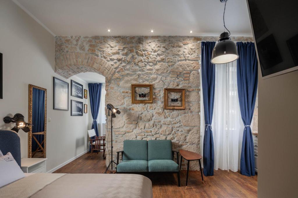 a bedroom with a blue chair and a stone wall at Photel studio Apartments in Crikvenica