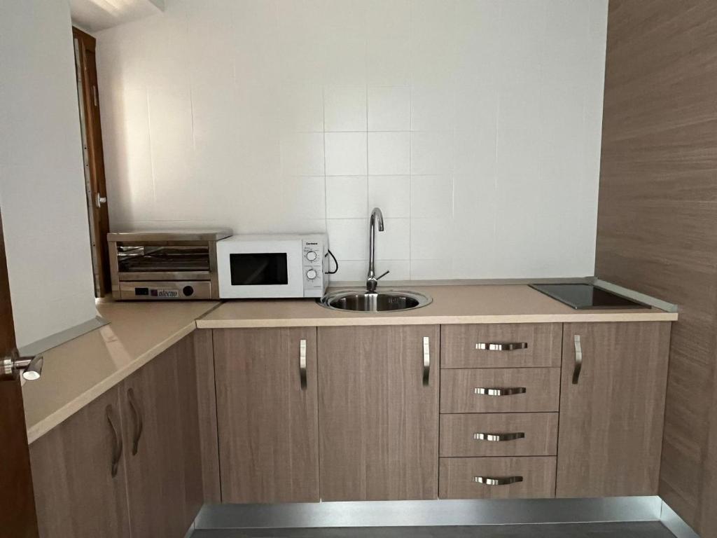 a small kitchen with a sink and a microwave at Clarisas Suites in Carmona