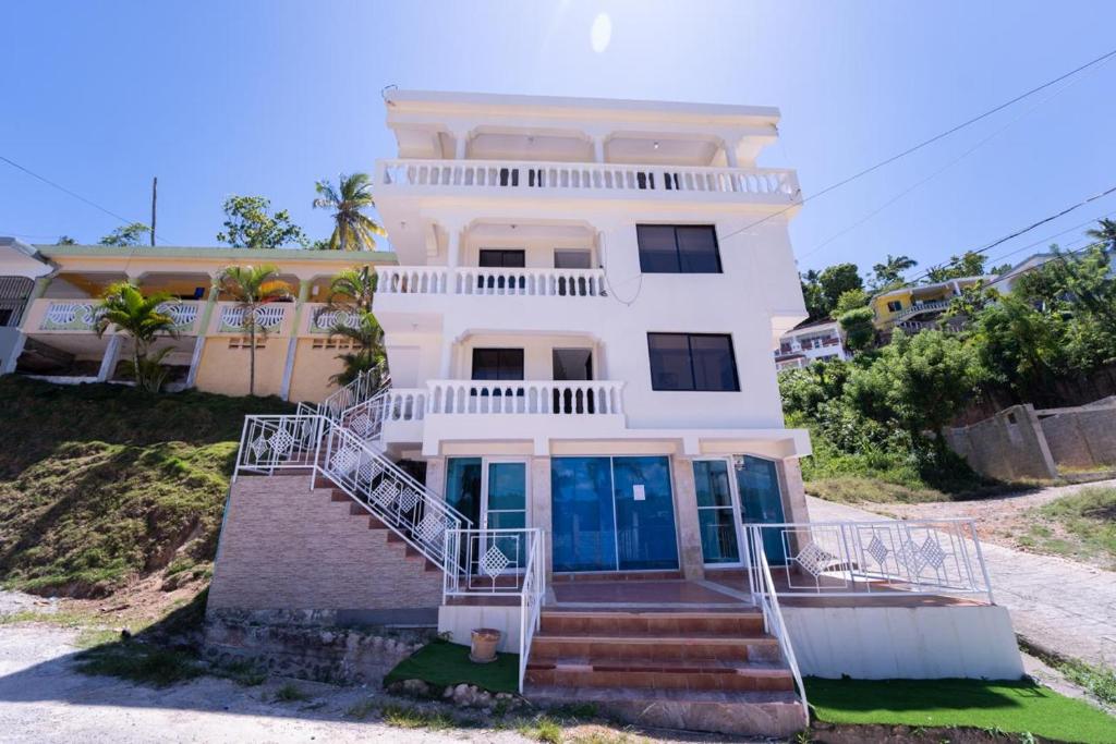 a large white house with stairs in front of it at Hotel porto escondido in Santa Bárbara de Samaná