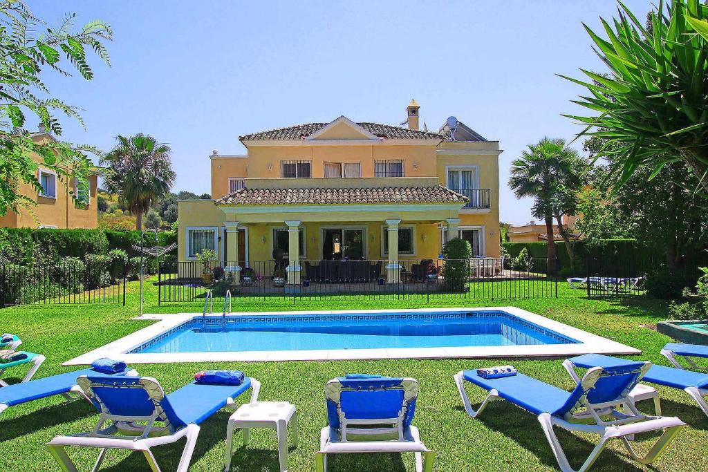 エステポナにある1106 Marbella Large Family Villaの芝生の椅子が備わるスイミングプール付きの家