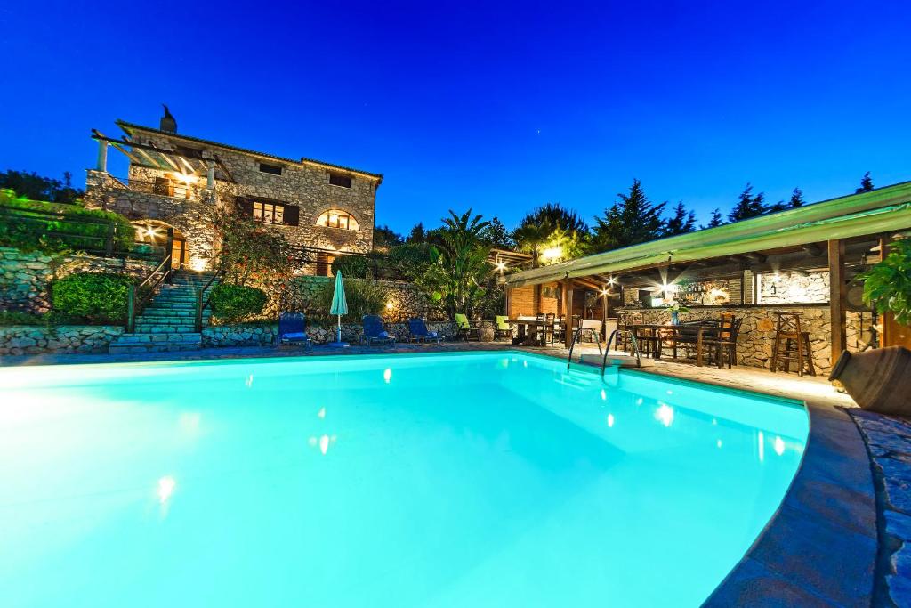 uma piscina em frente a uma casa à noite em Villa Poseidon Residence em Skinária