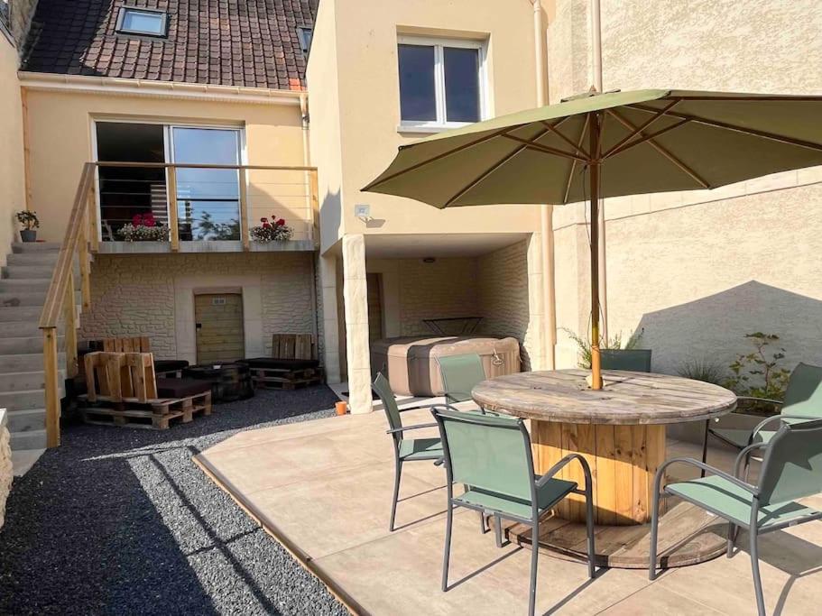 een patio met een tafel met stoelen en een parasol bij Gite Le Long de l'eau in Long