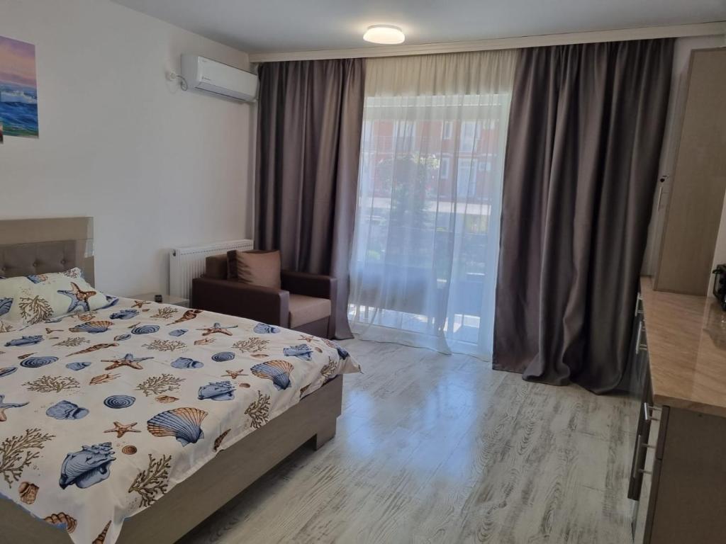 a bedroom with a bed and a chair and a window at Garsoniera Adriana in Mangalia