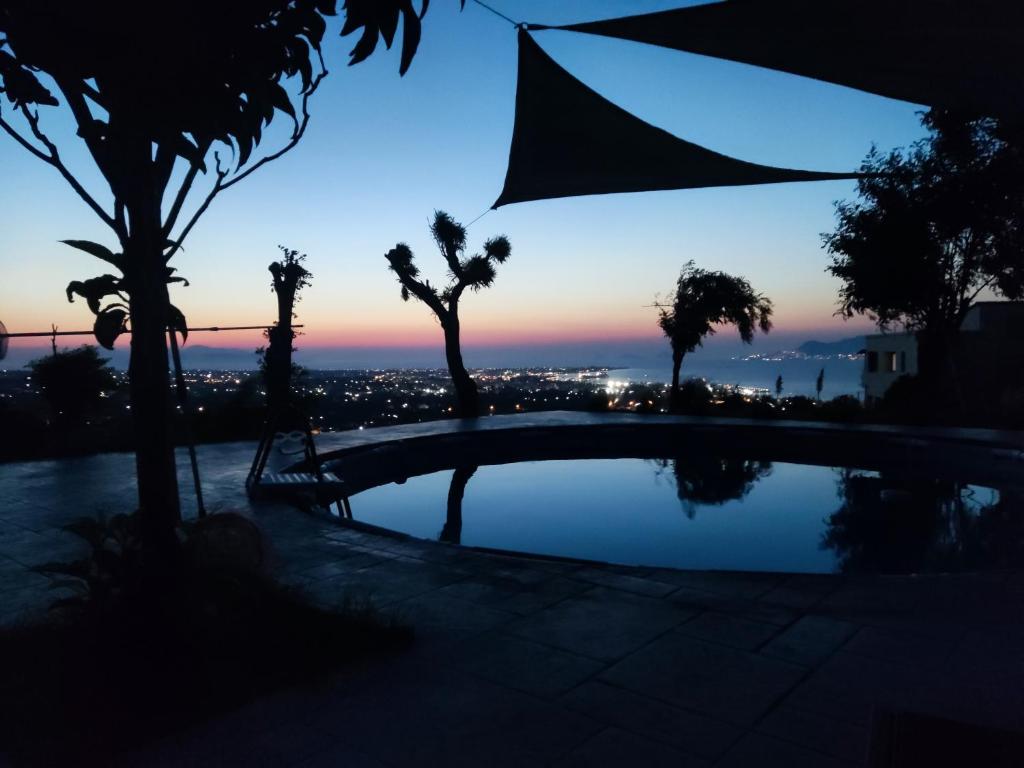 a dusk view of a swimming pool with palm trees at Yiorgos, amazing sunset view house in Psalidi