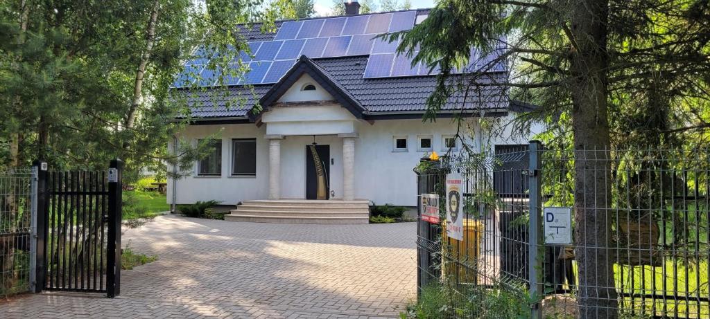 une maison blanche avec des panneaux solaires sur le toit dans l'établissement Domek na Mazurach-Piasutno, à Piasutno