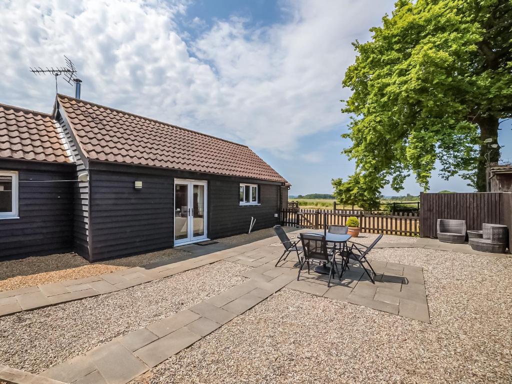 um pátio com uma mesa e cadeiras em frente a uma casa em Little Tree Cottage em Felmingham