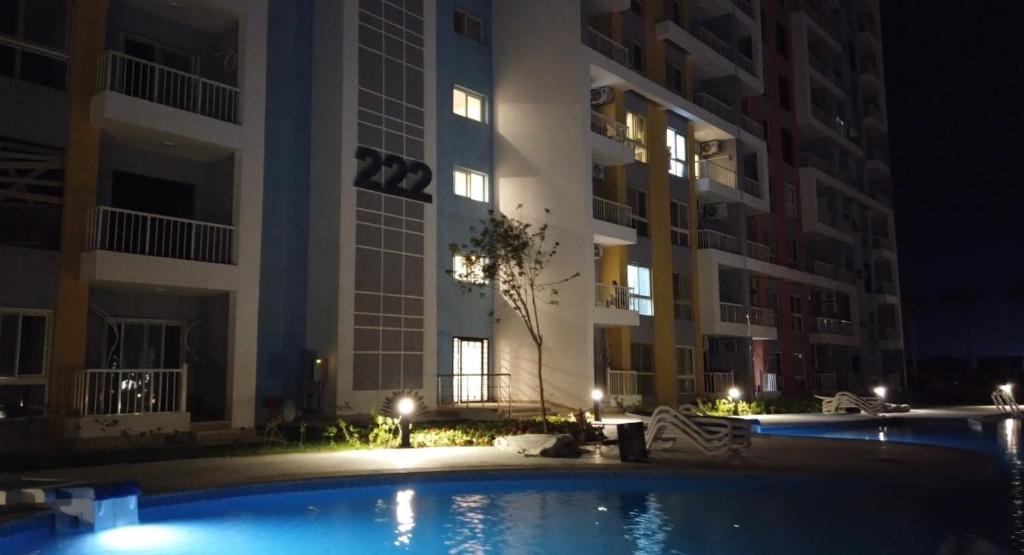 a swimming pool in front of a building at night at Cozy studio Porto golf in El Alamein