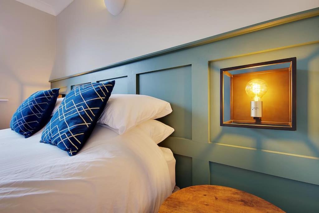 Bright and Cosy house with 3 bedroom 3 bathrooms في بورنموث: غرفة نوم مع سرير ووسائد زرقاء وبيضاء