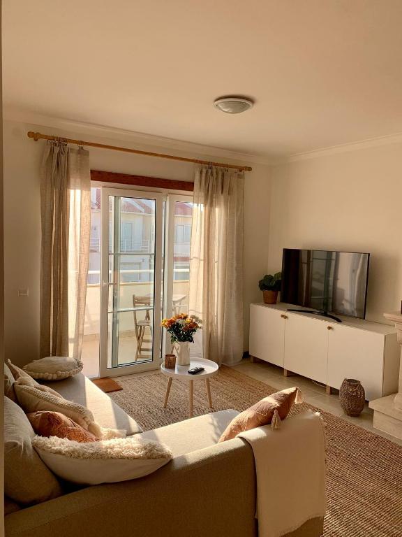 a living room with a couch and a tv at Nalu House Baleal - by the beach in Baleal