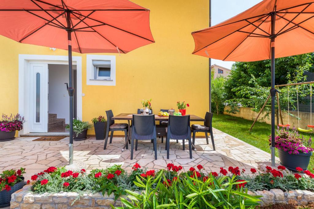 a patio with a table and chairs and umbrellas at Mala Harmonija in Vodnjan