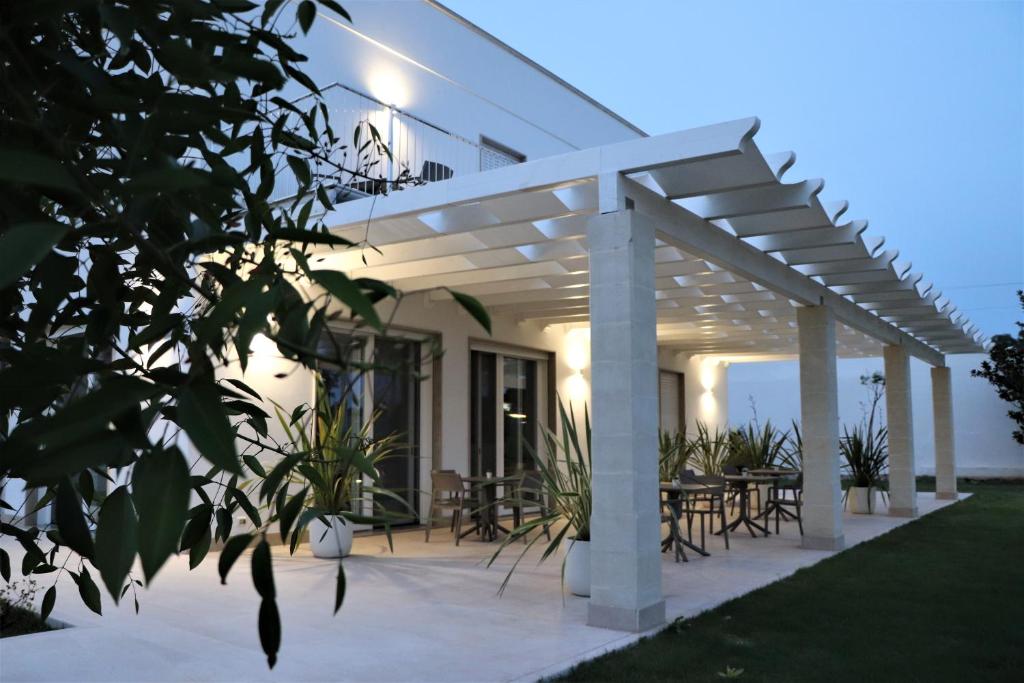 a white pergola with tables and chairs on a patio at Verde Blu Vacanze B&B in Torre Lapillo