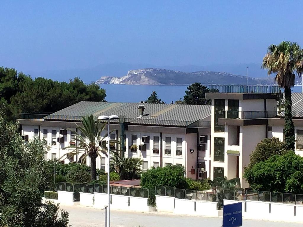 - un bâtiment blanc avec un palmier en face de l'océan dans l'établissement Mandorli, à Su Forti