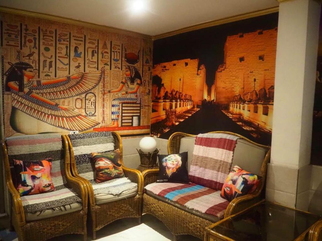 une chambre avec deux chaises et un mur orné d'une peinture dans l'établissement Venus hotel luxor 日本人 大歓迎, à Louxor