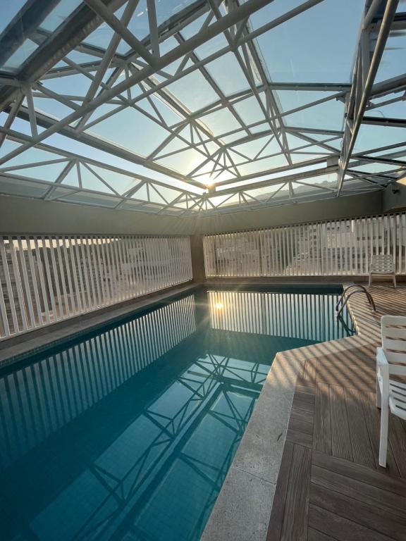 a swimming pool with two chairs and a table at NOVO pitangueiras service 2, dois dormitórios, 100 m da praia, duas vagas de garagem, completo in Guarujá