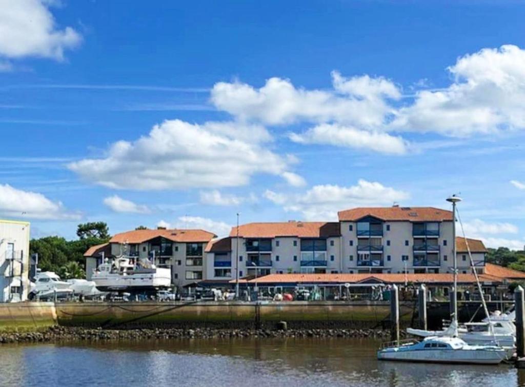a boat is docked in a marina next to a building at Horizon Océan 1 - Superbe appartement 2 pièces avec parking privatif in Capbreton