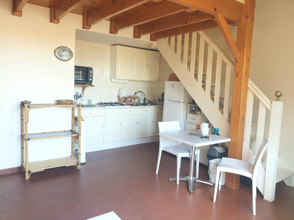 een keuken met witte kasten en een tafel en stoelen bij Apparemment à 200 m de l'étang et piste cyclable in Marseillan