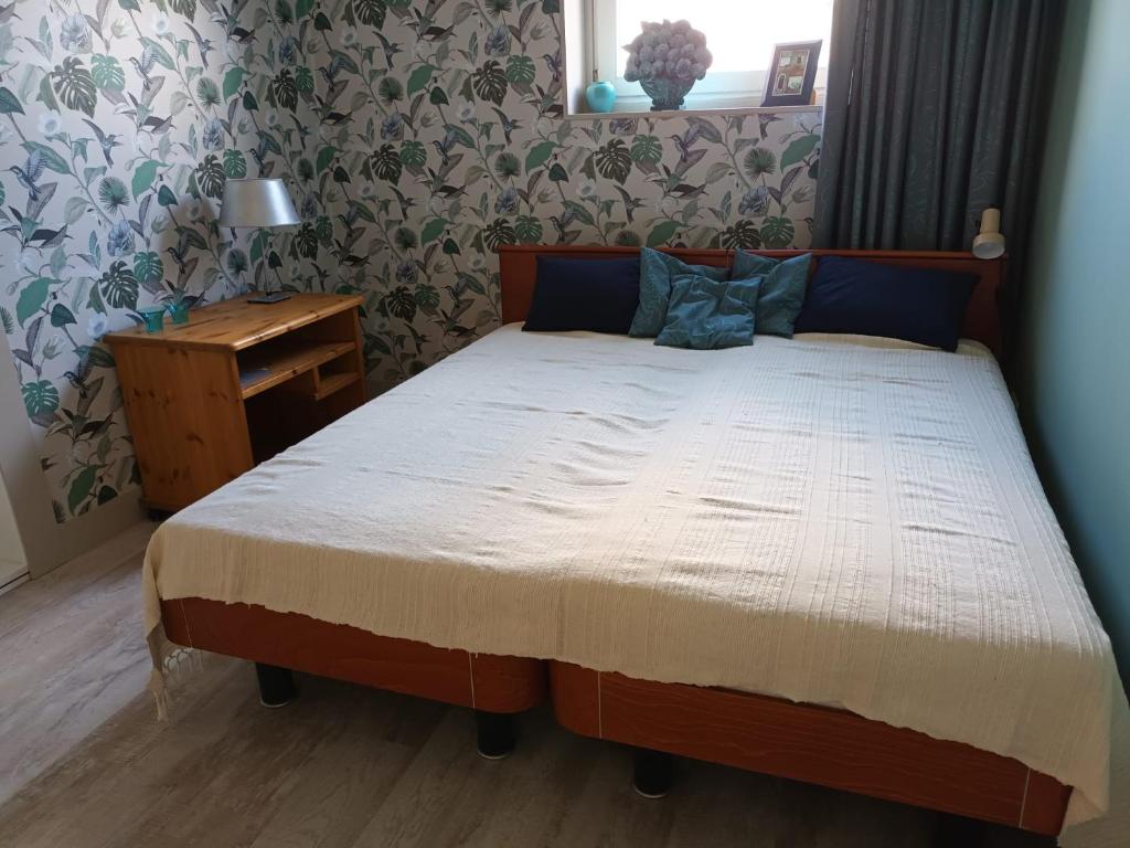 a bedroom with a bed and a night stand with a table at Bollenboet in Sint Maarten