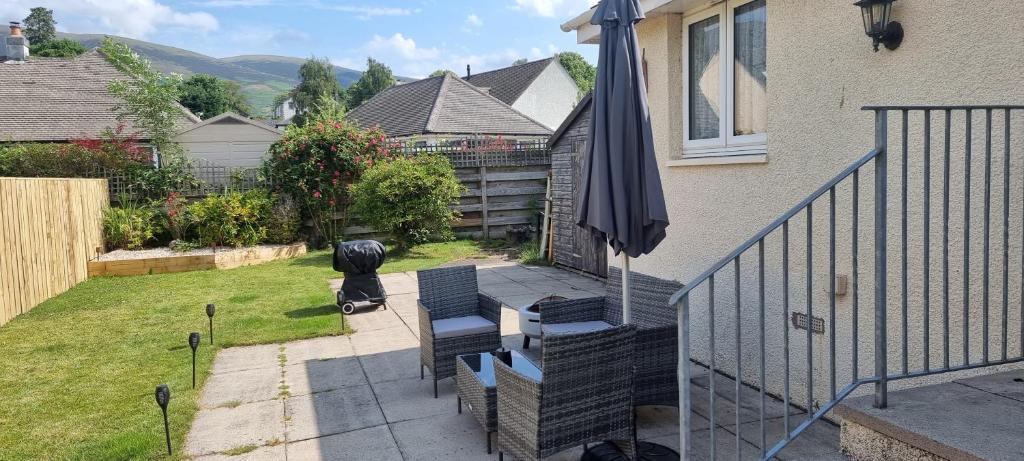 a patio with two chairs and an umbrella at Plum Cottage in Keswick