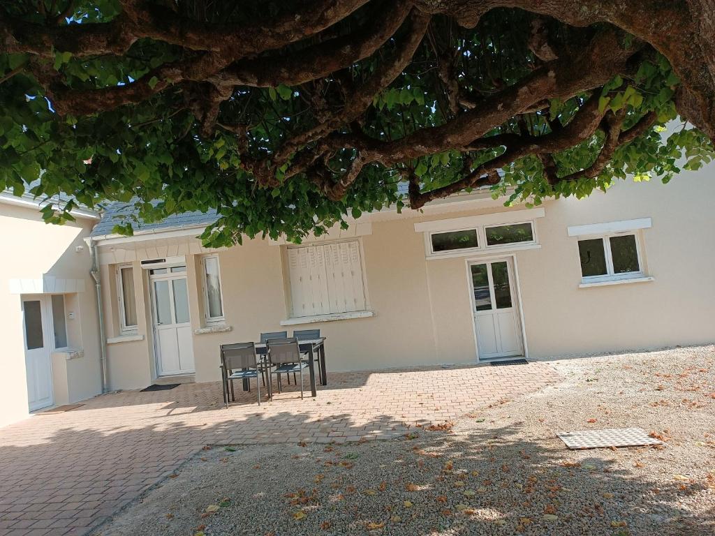 un bâtiment avec des chaises et une table sous un arbre dans l'établissement Les ROSEAUX A la Campagne au centre des chateaux de la Loire, à Feings