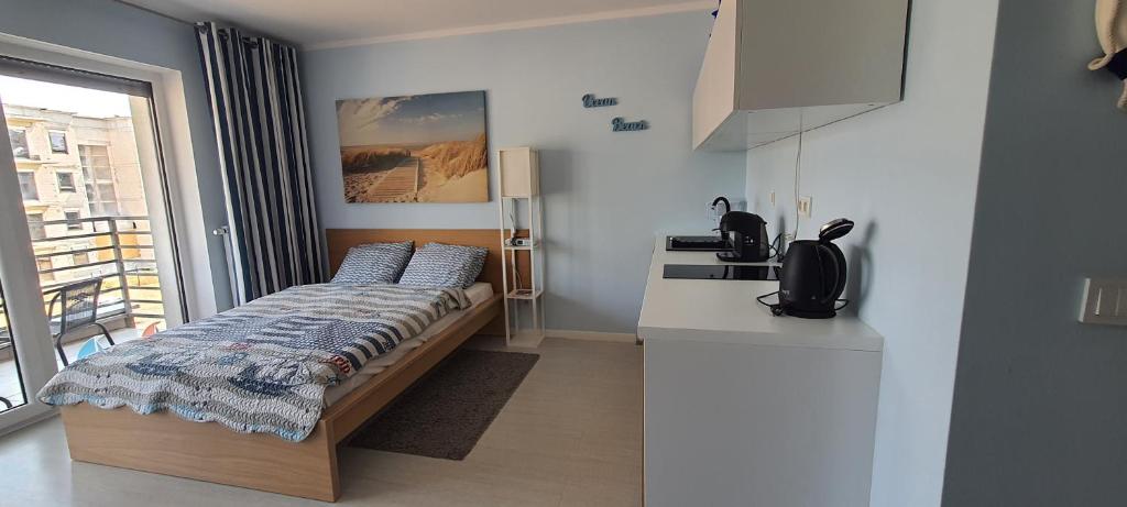 a small bedroom with a bed and a kitchen at Apartament Pogorzelica in Pogorzelica