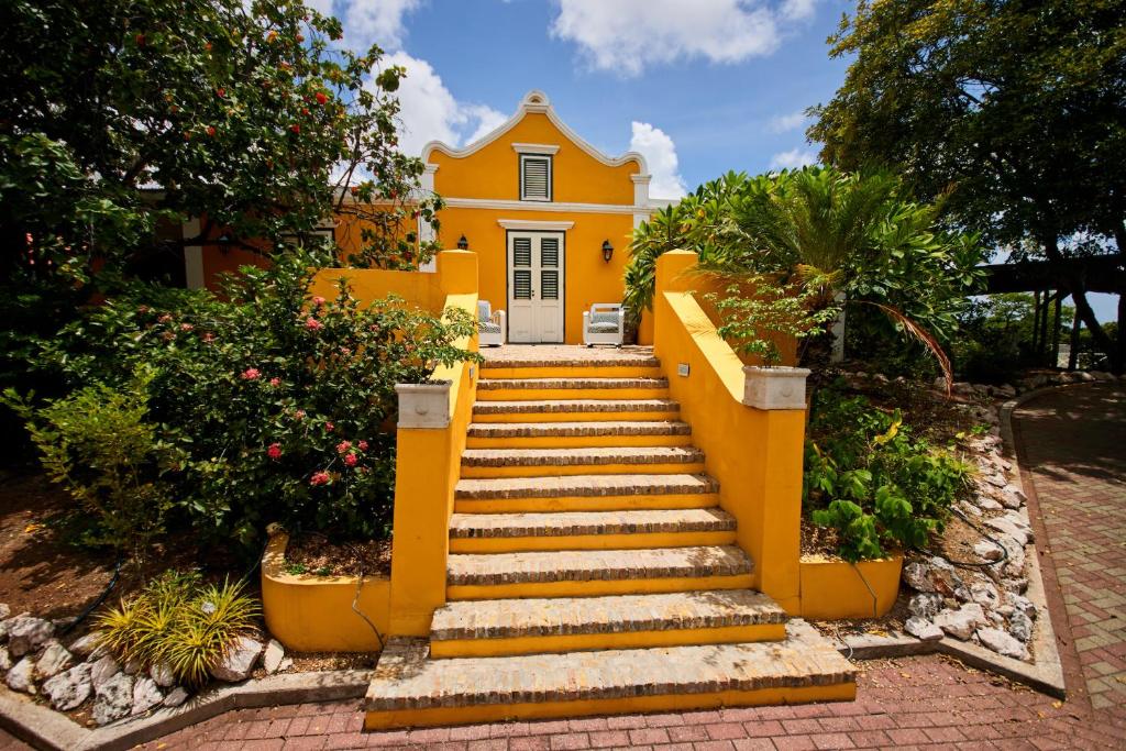 una casa amarilla con escaleras delante en Landhuis Bona Vista, en Willemstad