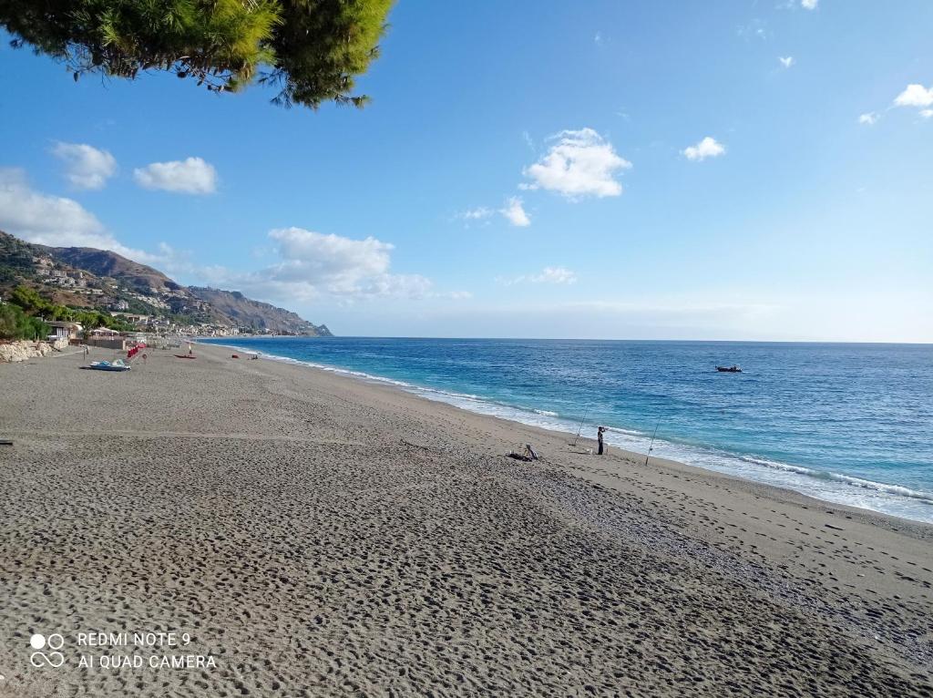 a beach with people and the ocean on a sunny day at Casa vacanze Leto in Letojanni