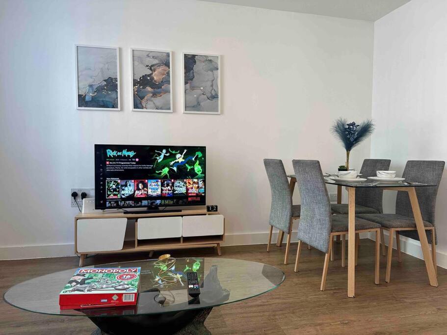 a living room with a television and a table with chairs at New Build 2 Bedroom Luxury Apartment, Jewellery Quarter Birmingham in Birmingham